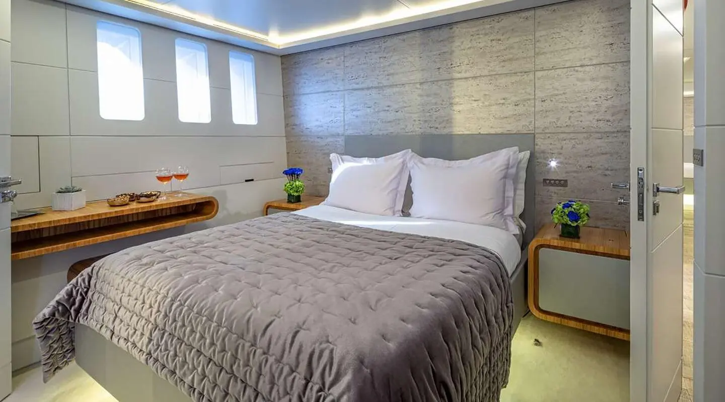 Interior bedroom with large bed, white pillows, and side tables with flowers