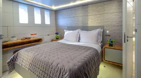 Interior bedroom with large bed, white pillows, and side tables with flowers