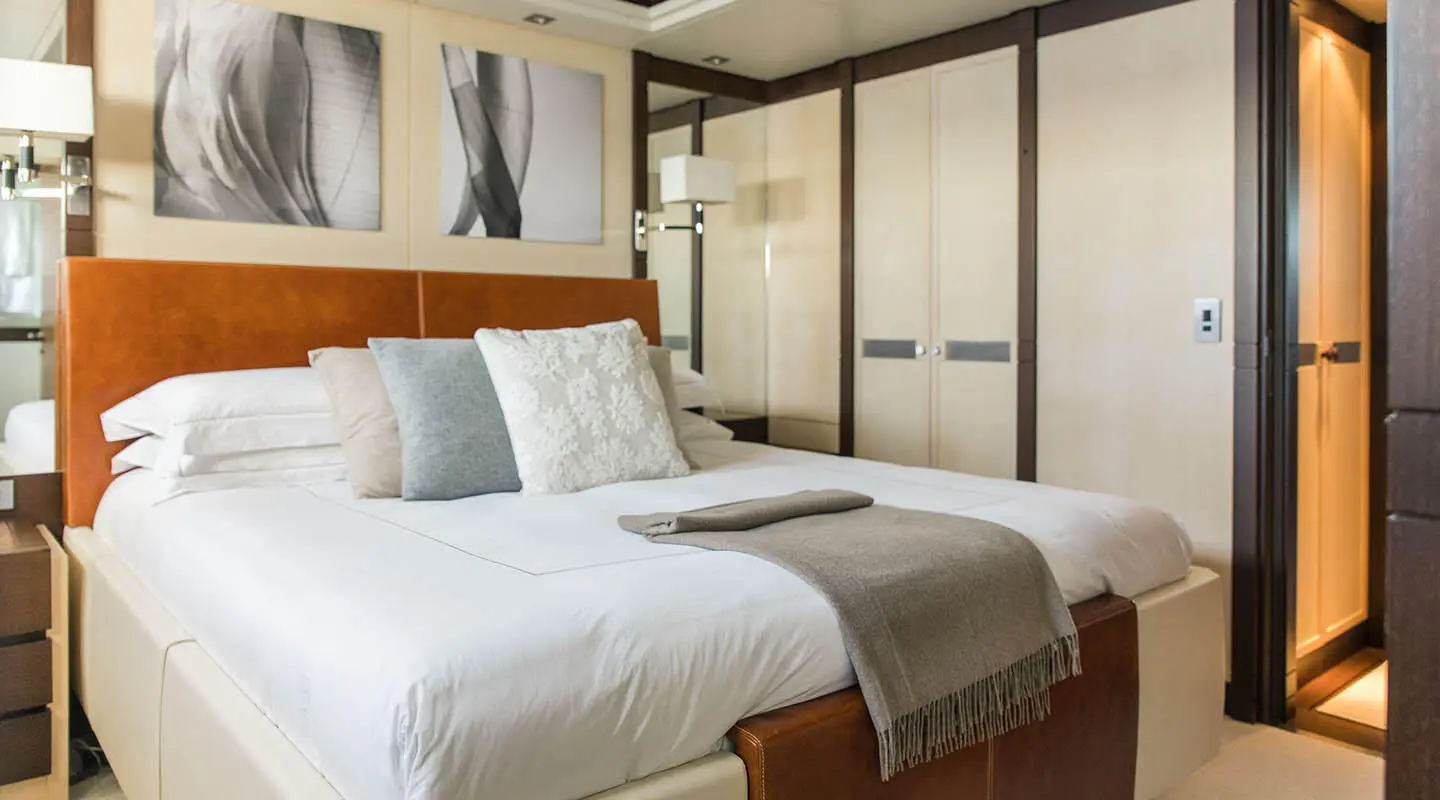 Luxurious yacht Alalya interior with a plush bed, pillows, and warm wood accents