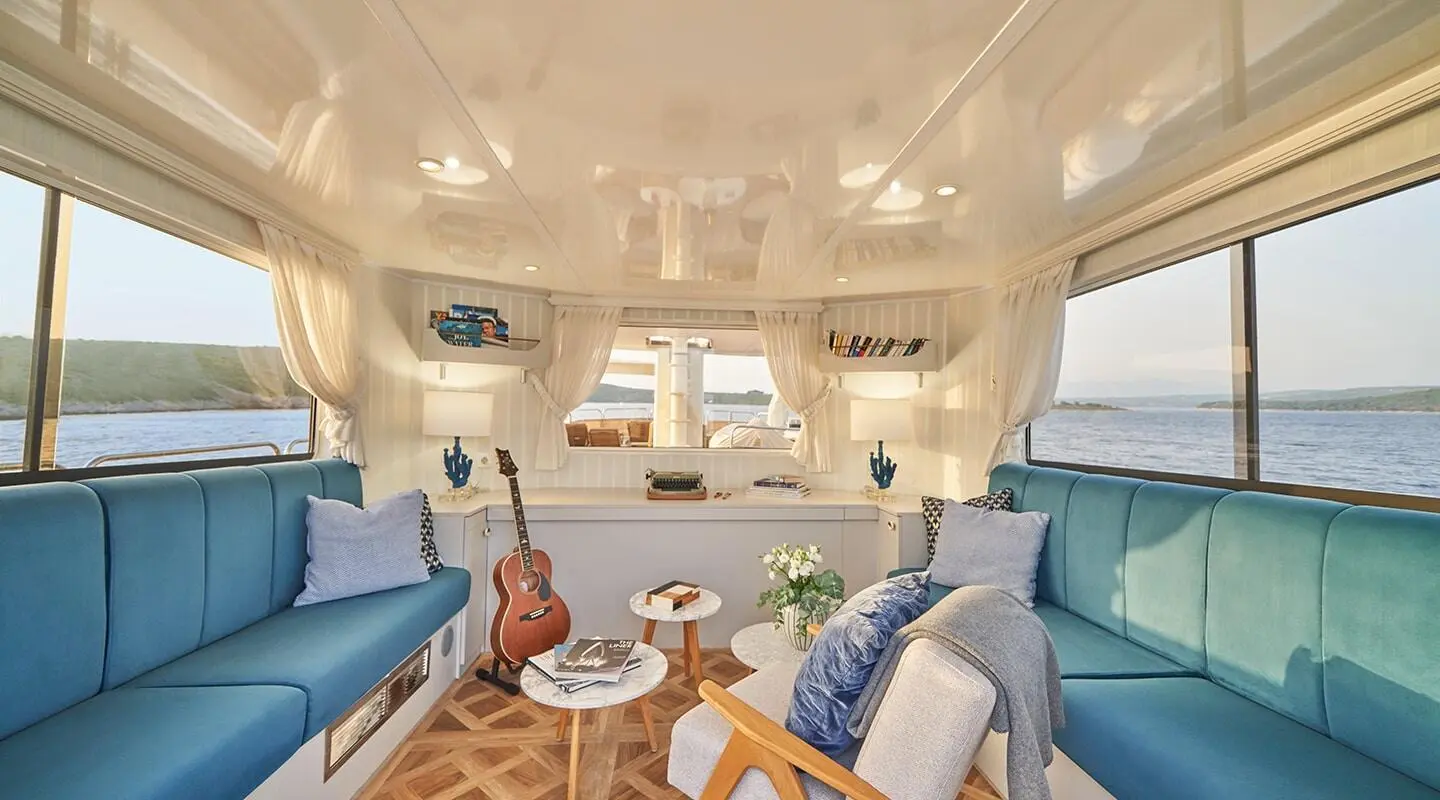 La Perla yacht lounge area with blue and white seating and sunlit cabin