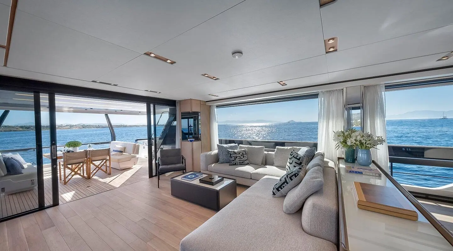 Spica luxury yacht interior: sunlit salon with plush L-shaped sofa and sea view
