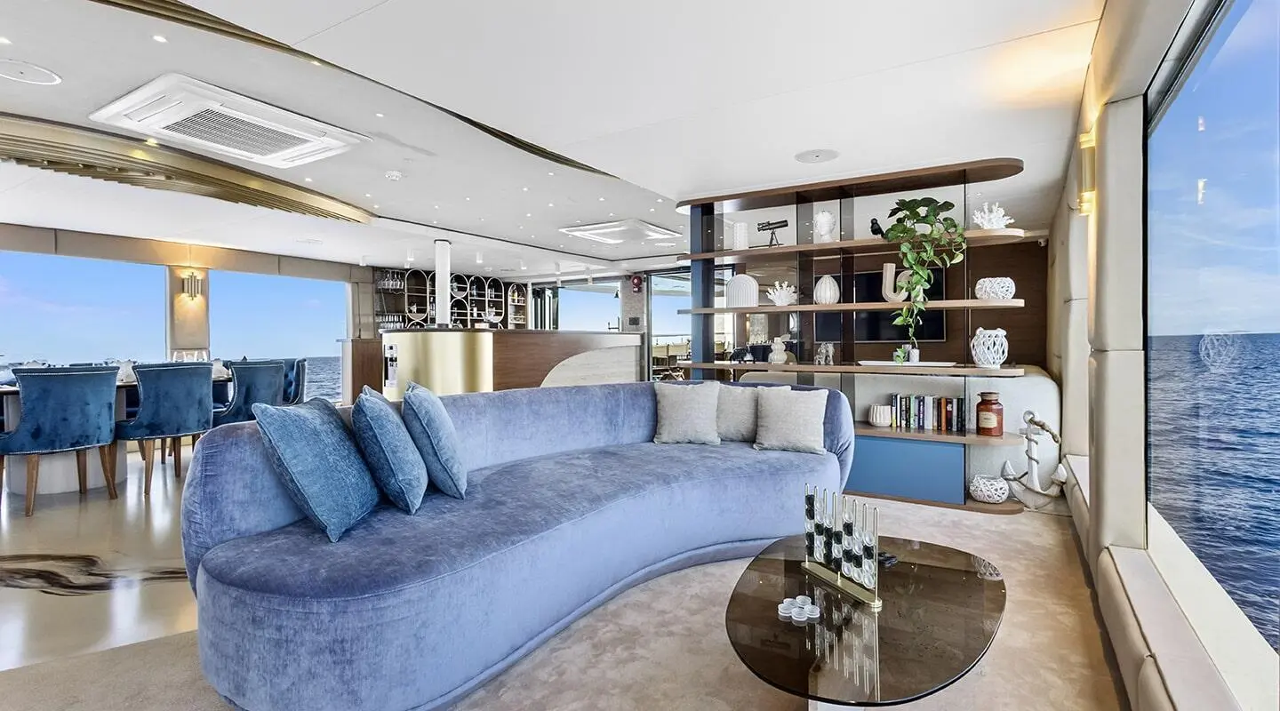 Cozy yacht salon with blue cushioned seating facing a bar and shelves