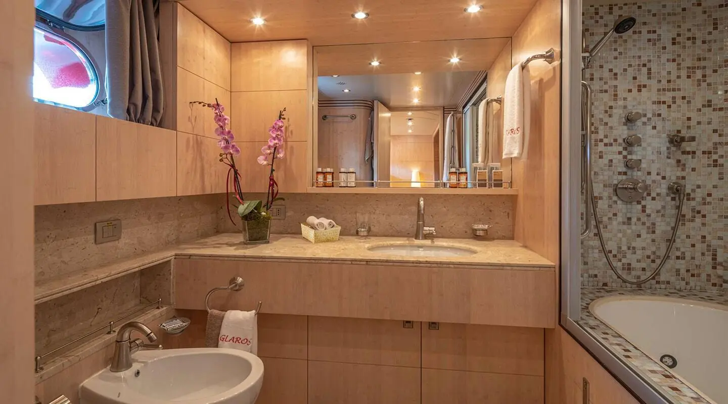 Glaros yacht bathroom with marble sink, mirror, and soft amber lighting