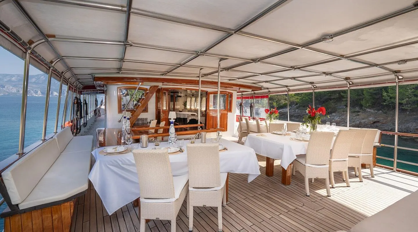 Aft deck seating area on Barbara yacht with white chairs and covered lounge space