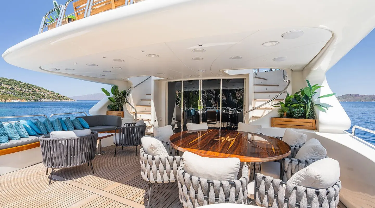 Amadea yacht aft deck with teak table, chairs, and door to interior