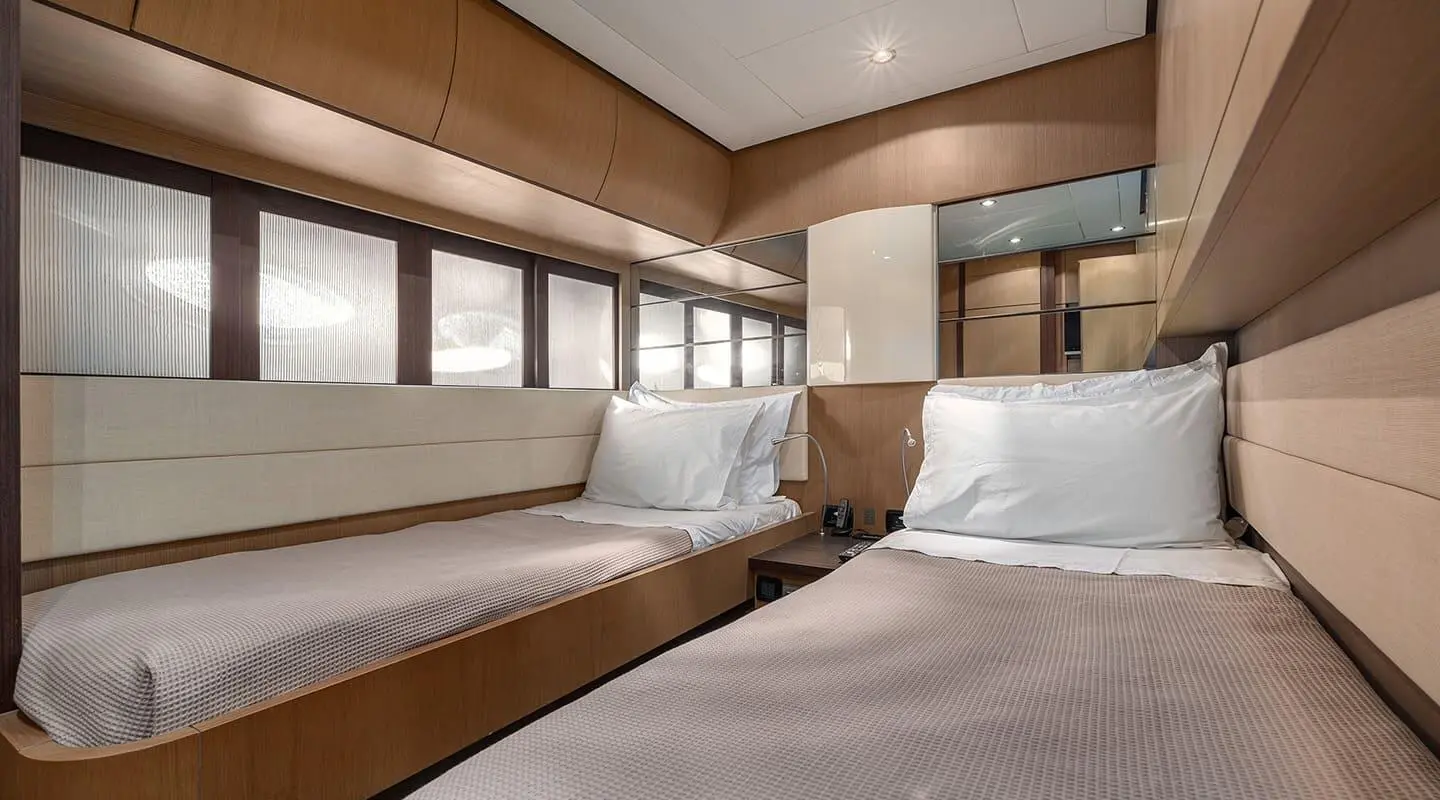 Cozy yacht bedroom with two single beds, wooden paneling, and windows