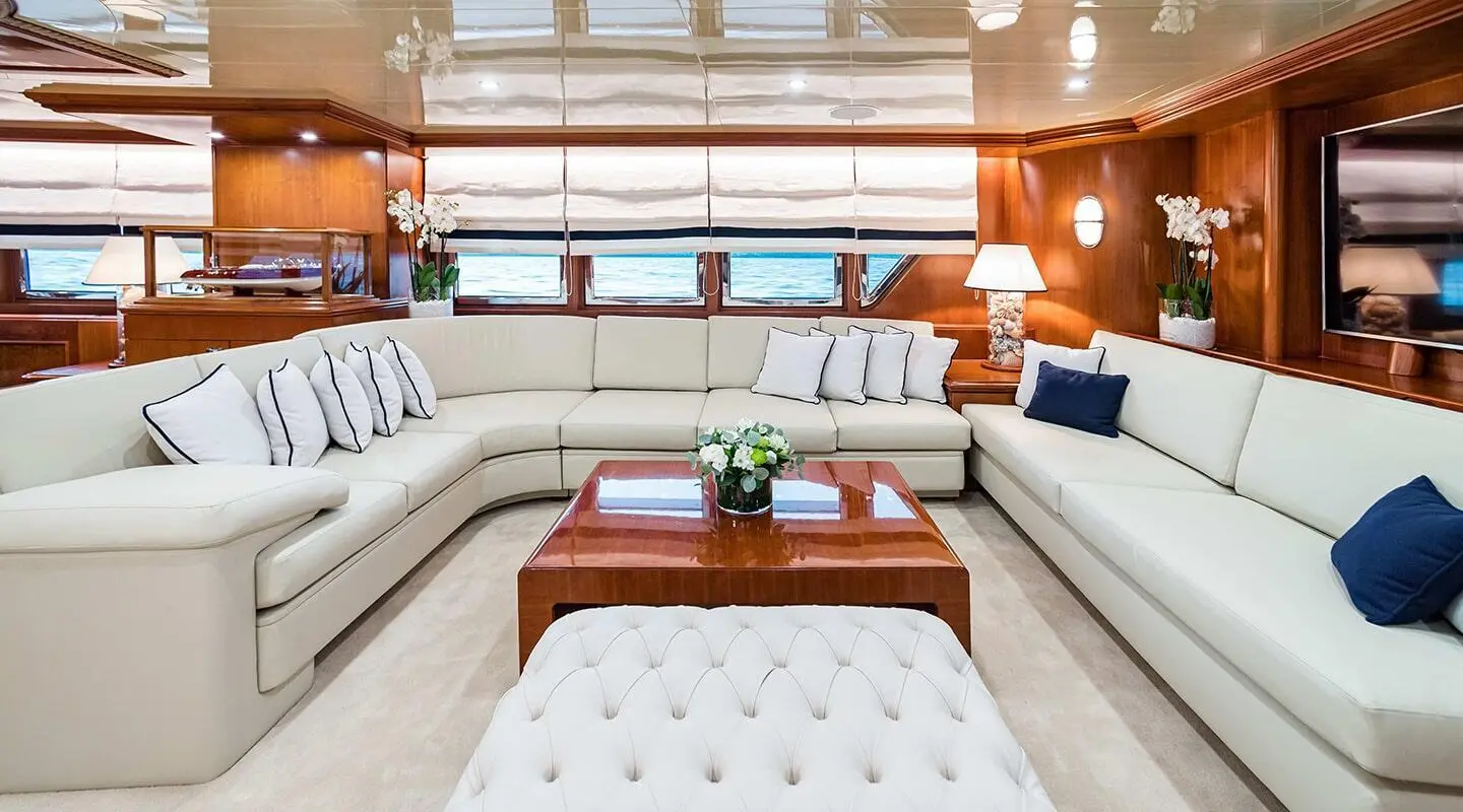 Interior shot aboard Wind Of Fortune with white tufted seating and wooden coffee table
