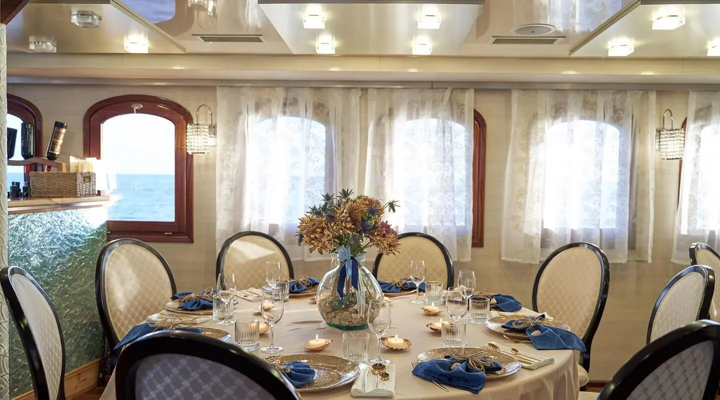 Casablanca yacht dining scene with a long table set for guests at sunset, elegant chandeliers
