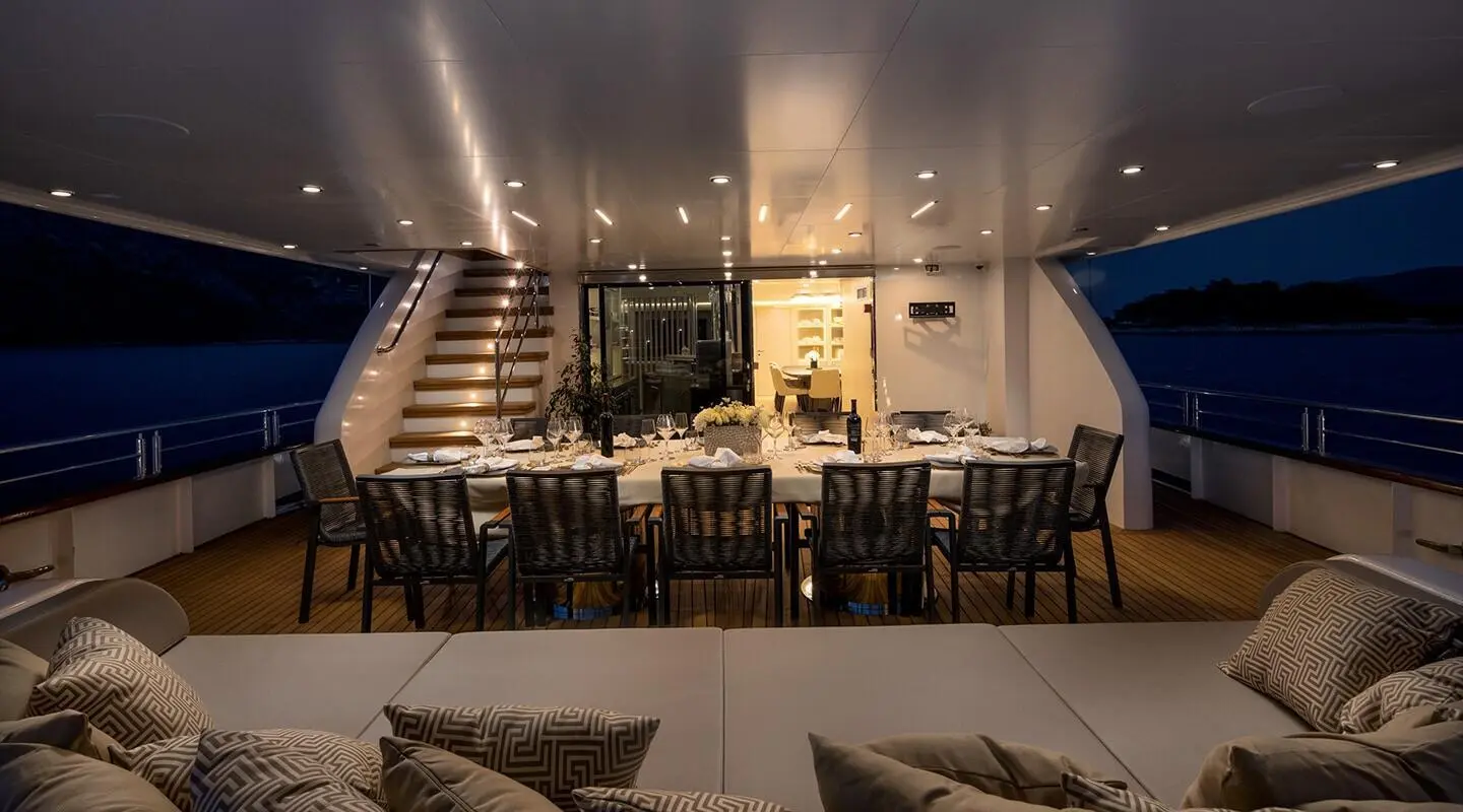 Love Story yacht interior at night with dining table set for guests on deck