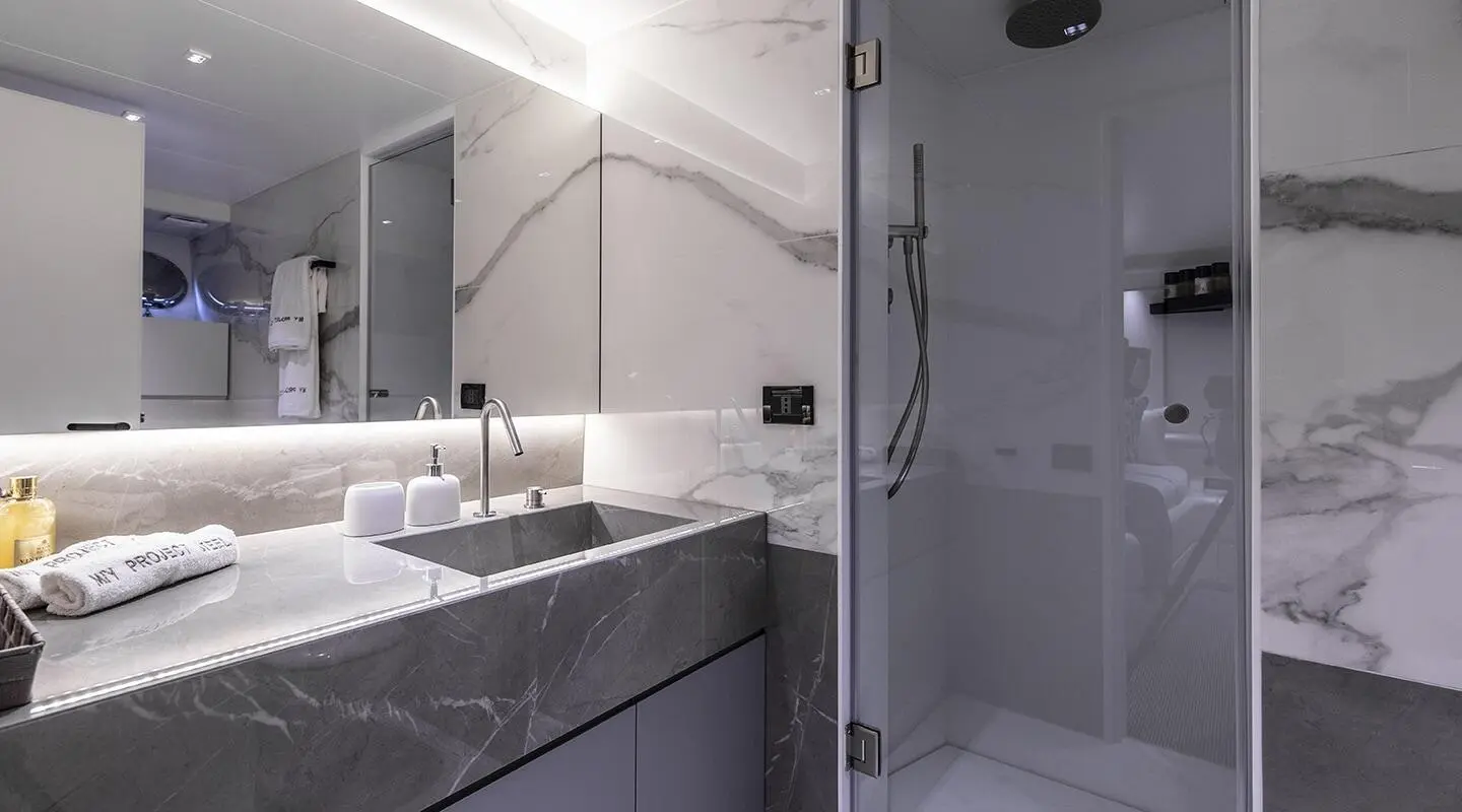 Luxurious yacht bathroom on Project Steel featuring marble countertops and a glass shower