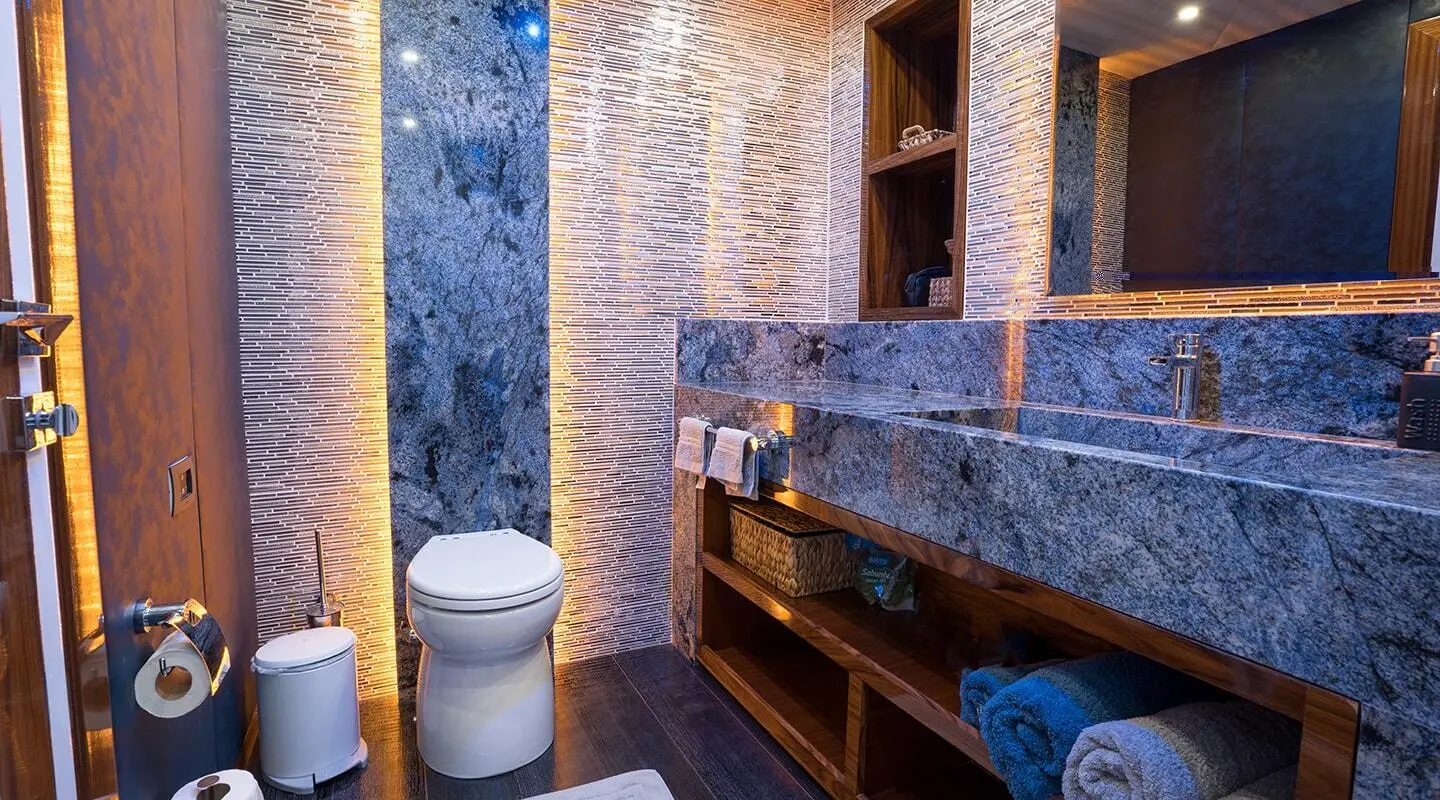 Gulet-style yacht bathroom with tiled walls, blue fixtures, and wooden accents