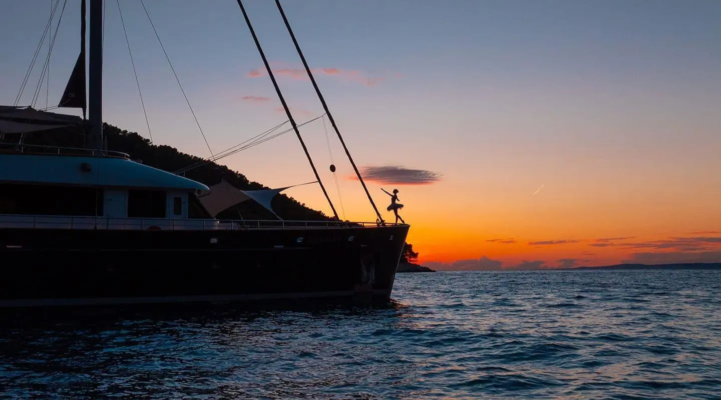 Silhouetted motor yacht Dalmatino at sunset on tranquil water