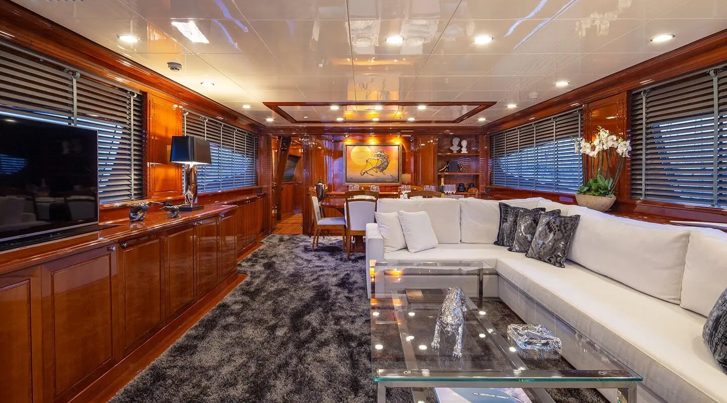 Interior of Divine 29m yacht with wood cabinets, seating area, and glass staircase