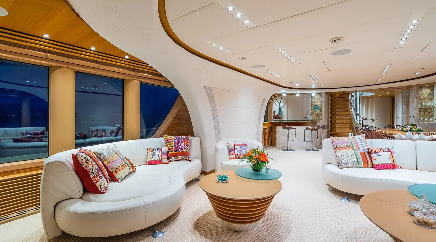 Interior of Serenity yacht saloon with curved white furnishings and wooden accents