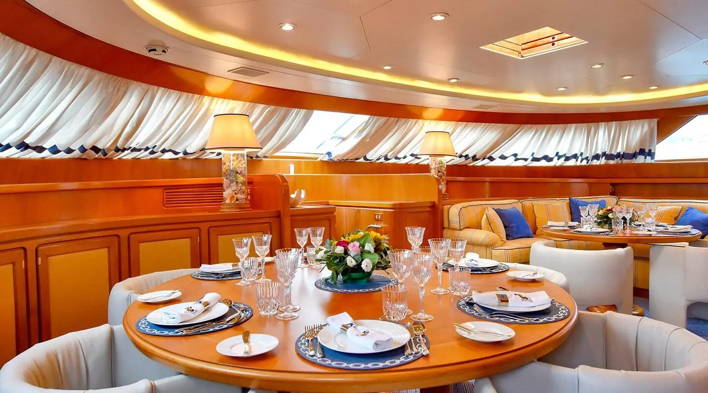 Dining area aboard Tamarita yacht with plated table setting and floral centerpiece