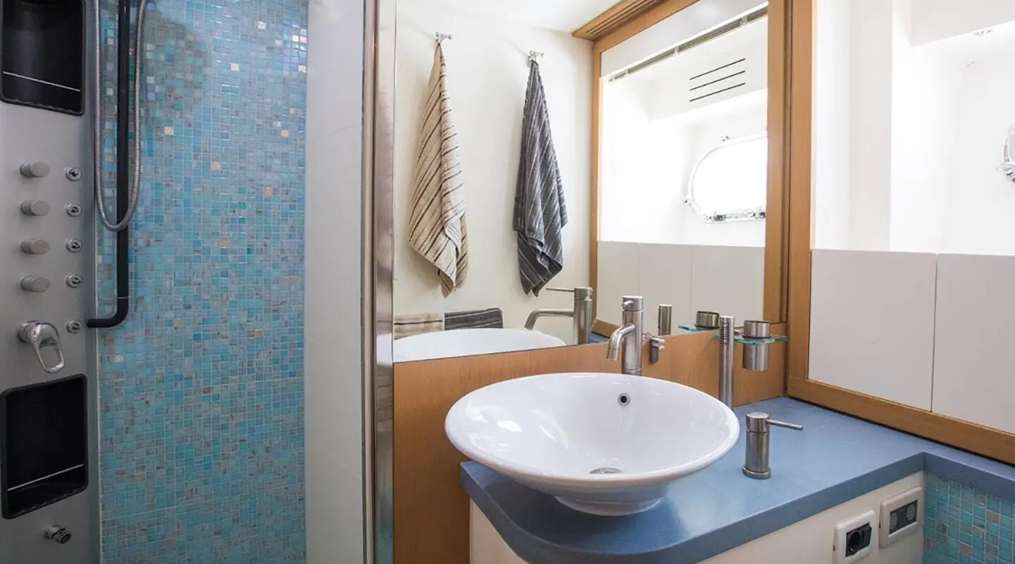 Bathroom on Salt yacht with round sink, mirror, towels, and wooden accents