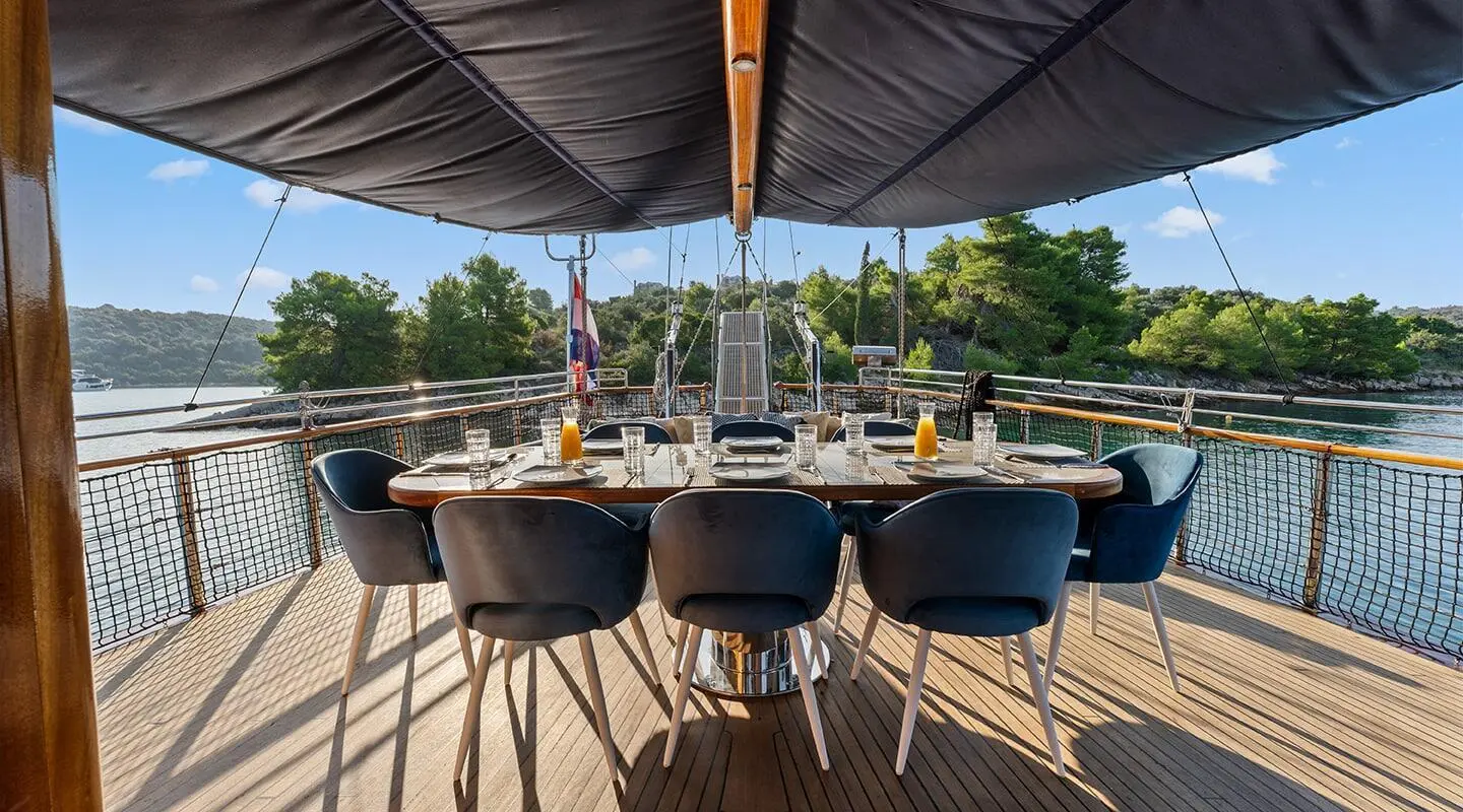 Aft deck of gulet Smart Spirit with wooden chairs under shade sail, docked.