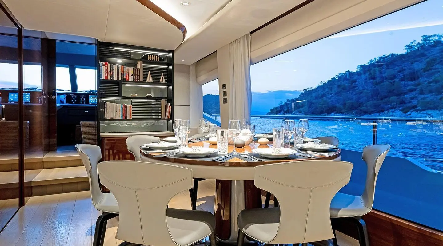 Vista yacht dining area at sunset with table set and blue sea view