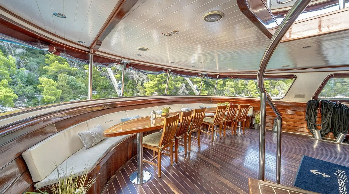 Cesarica yacht interior deck at sunset with wooden railings and seating
