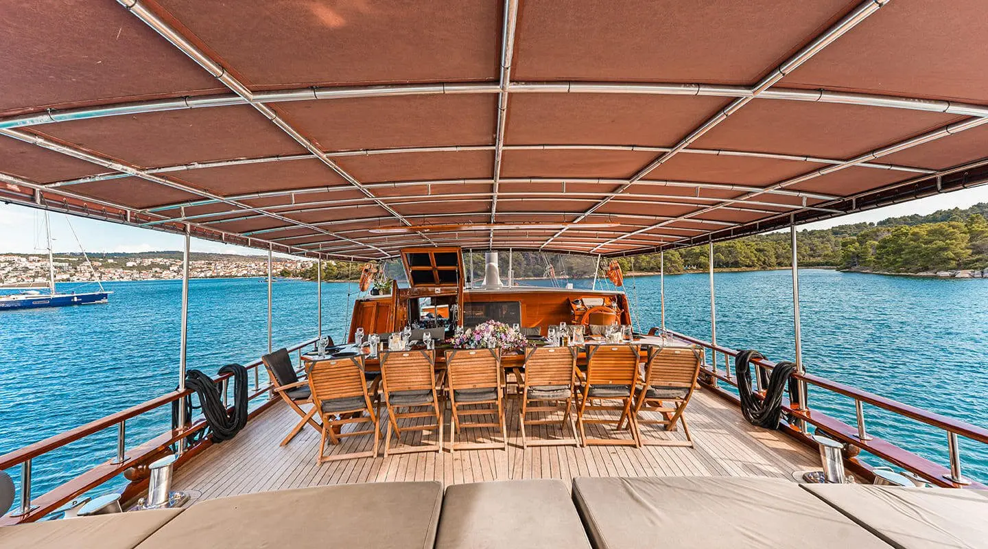 Elegant yacht deck with seating under a shaded canopy at sunset on calm blue water