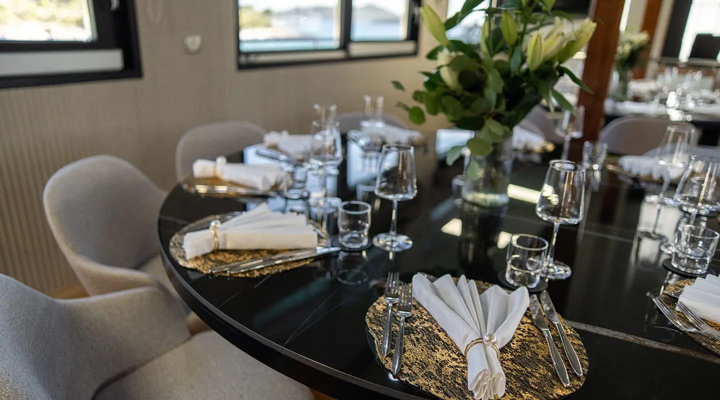 Interior dining area aboard Karizma yacht with table settings and windows