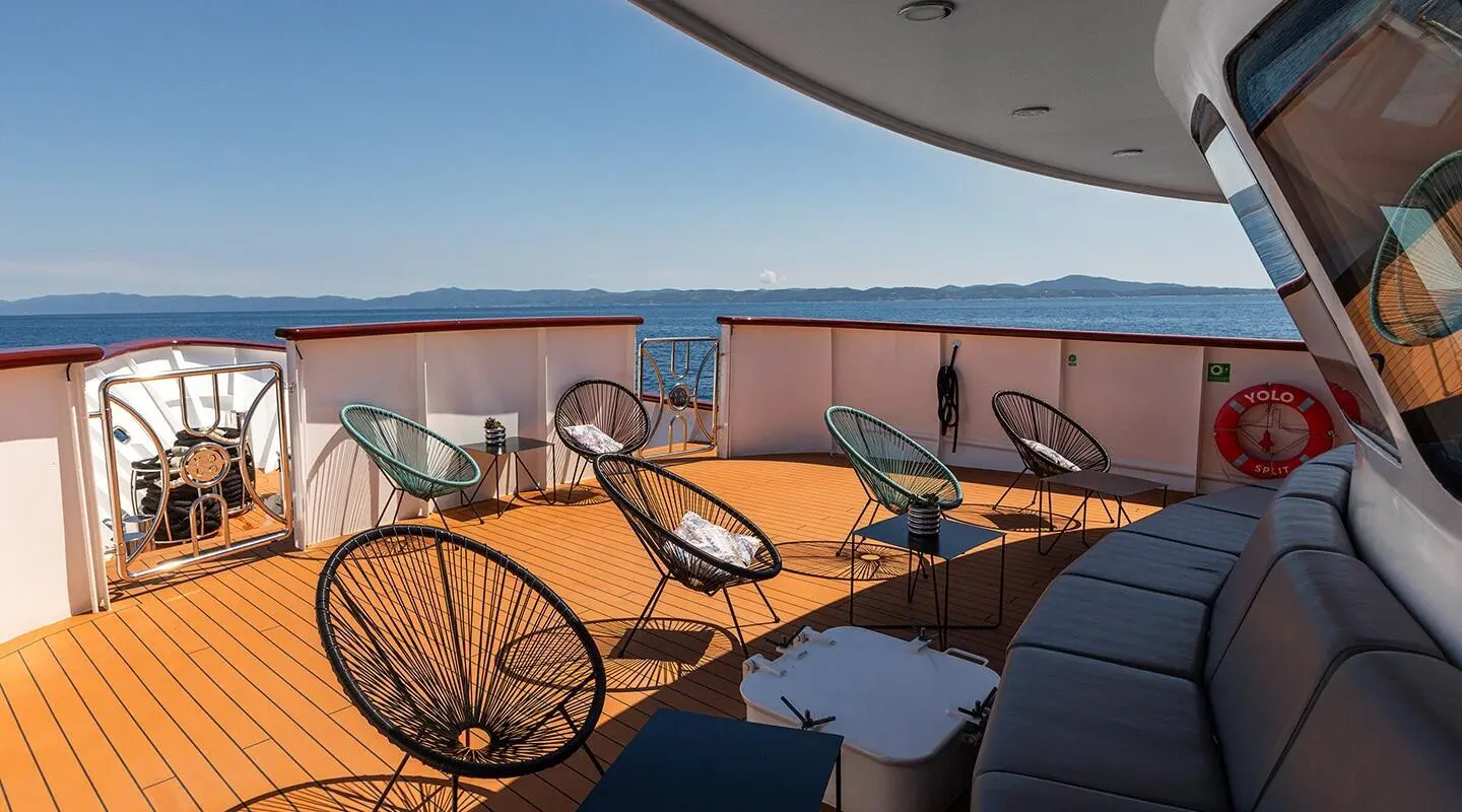 Yacht deck seating area at sunset with wicker chairs and wooden table