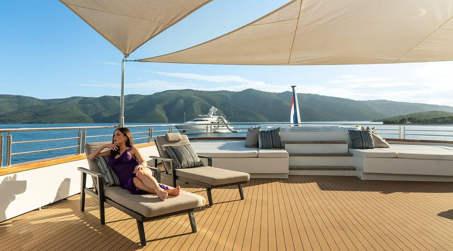 Woman in purple dress lounging on sun deck of Cristal yacht