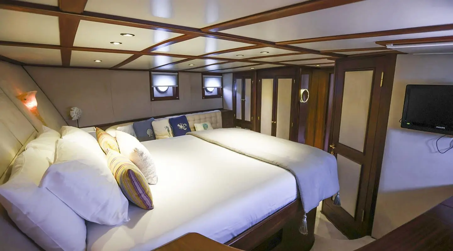 Gazella luxury gulet interior: two white beds, wood paneling, windows