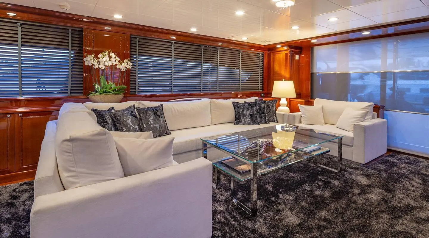 Luxurious yacht saloon with large windows, sectional sofa, and marble coffee table