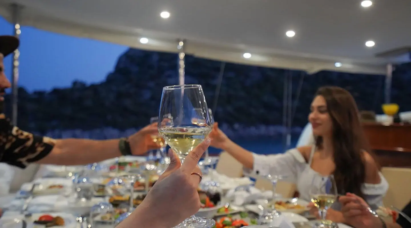 Evening yacht dining scene with people clinking glasses around a long table
