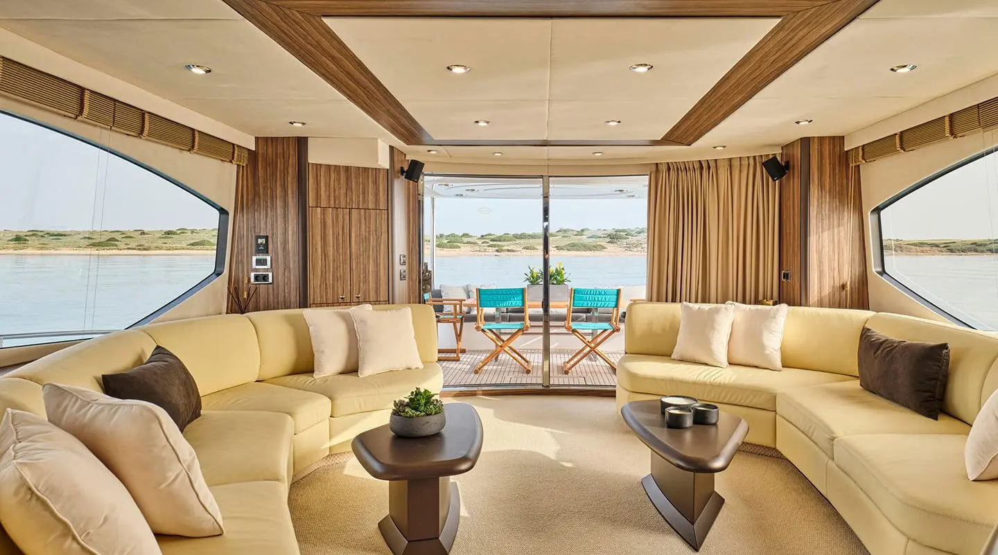 Luxurious yacht lounge with beige sofas, coffee tables, and sea view