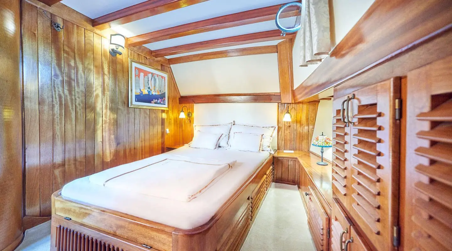 Luxurious yacht Libra cabin with wood paneled walls and bed in center