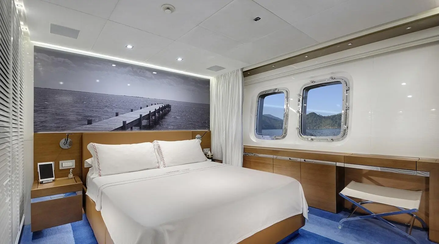 Morning Star yacht interior: two white beds, framed wall art, desk, windows, and blue carpet