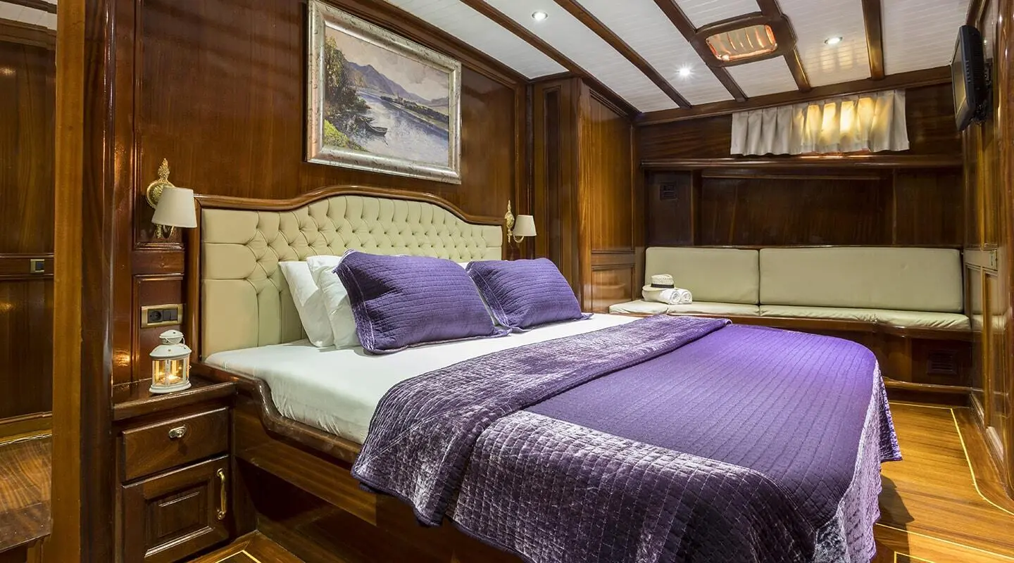 Grace 1 interior cabin with purple bedspread and wooden paneling