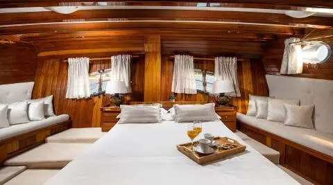 Andi Star yacht interior with polished wood, portside bed and white linens