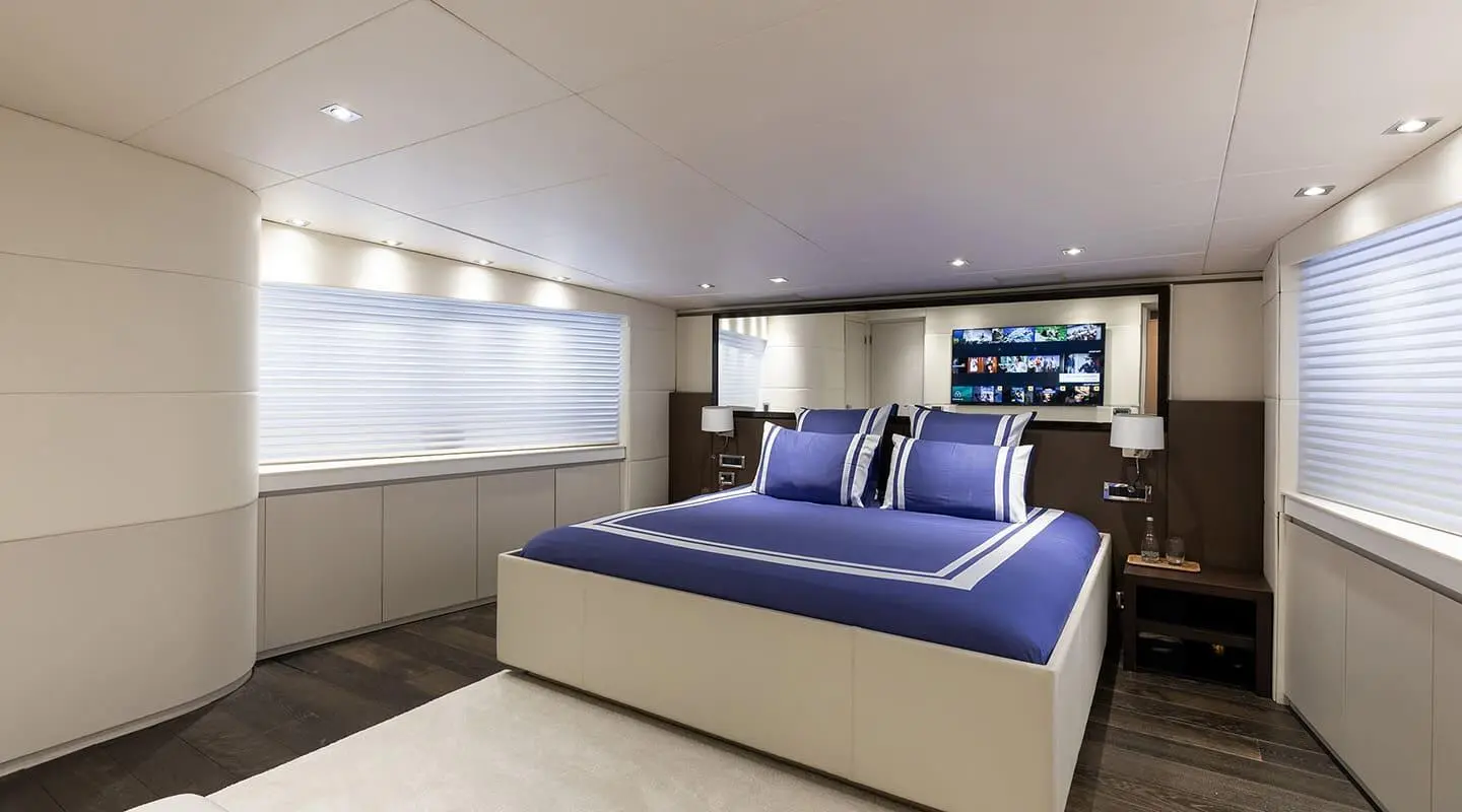 Luxurious yacht bedroom with a large bed, blue pillows, and ambient lighting