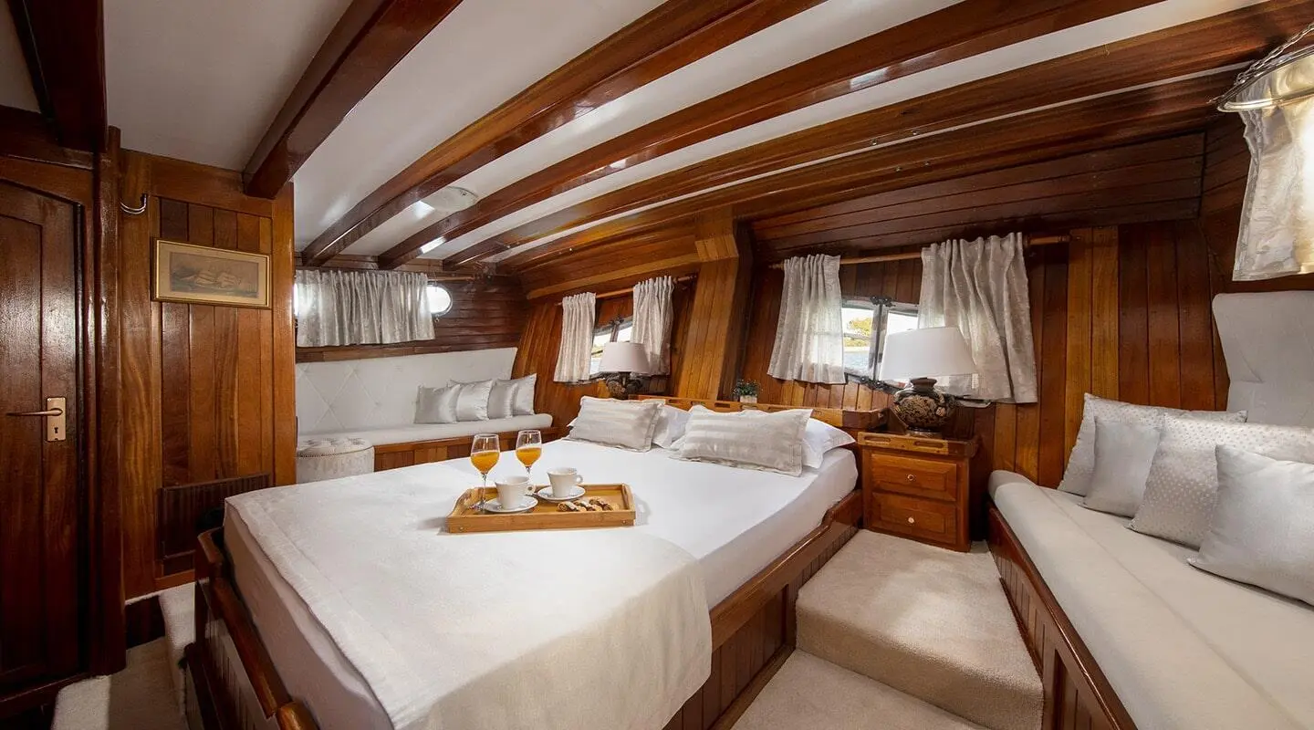 Andi Star yacht cabin with two beds, wooden ceiling, and porthole window