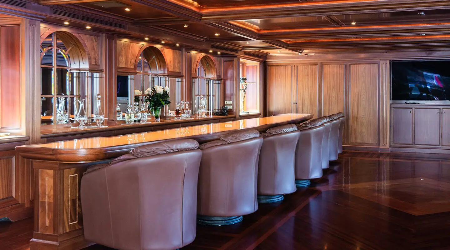 Interior bar area on Apogee yacht with high stools and warm lighting