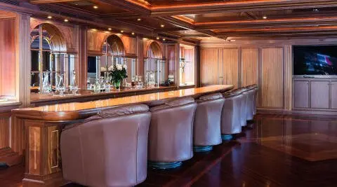 Interior bar area on Apogee yacht with high stools and warm lighting