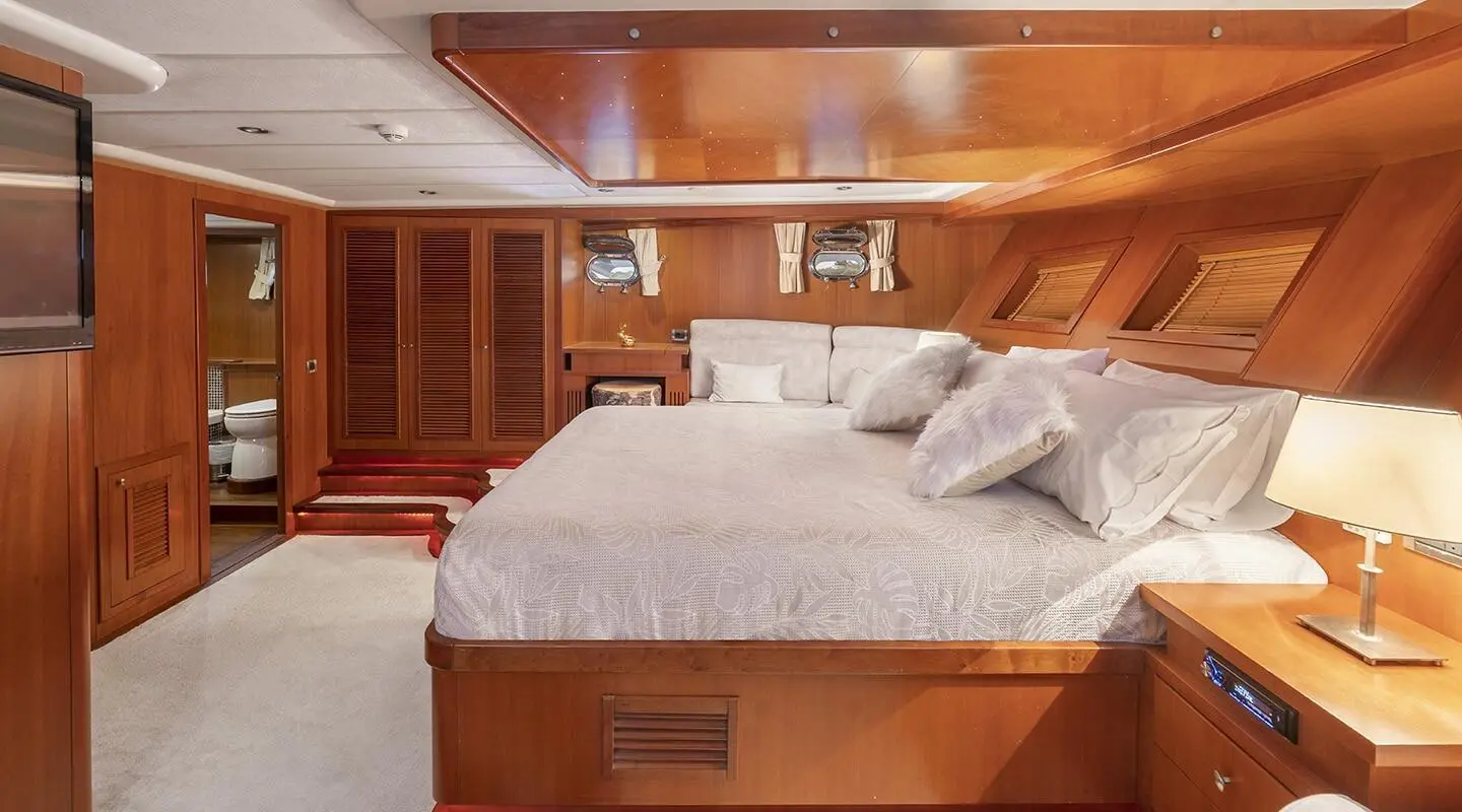 Arabella yacht master cabin with bed and wooden cabinetry inside softly lit space