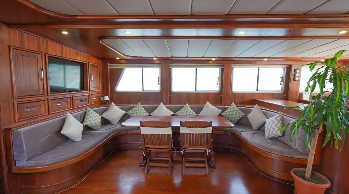 Luxurious yacht saloon with cream seating, wooden floor, windows, and table