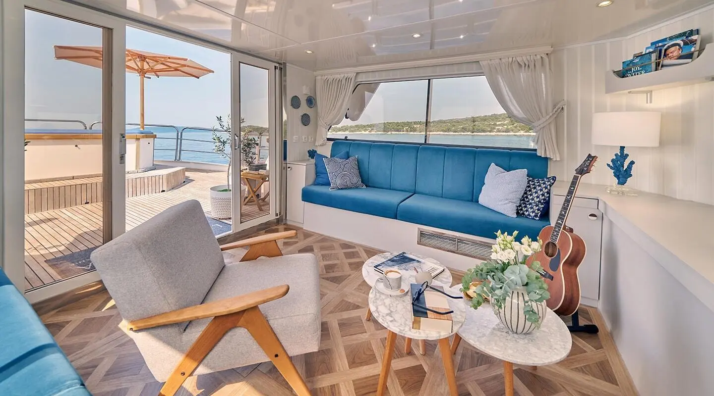 La Perla yacht lounge area with blue cushions and wooden deck chairs