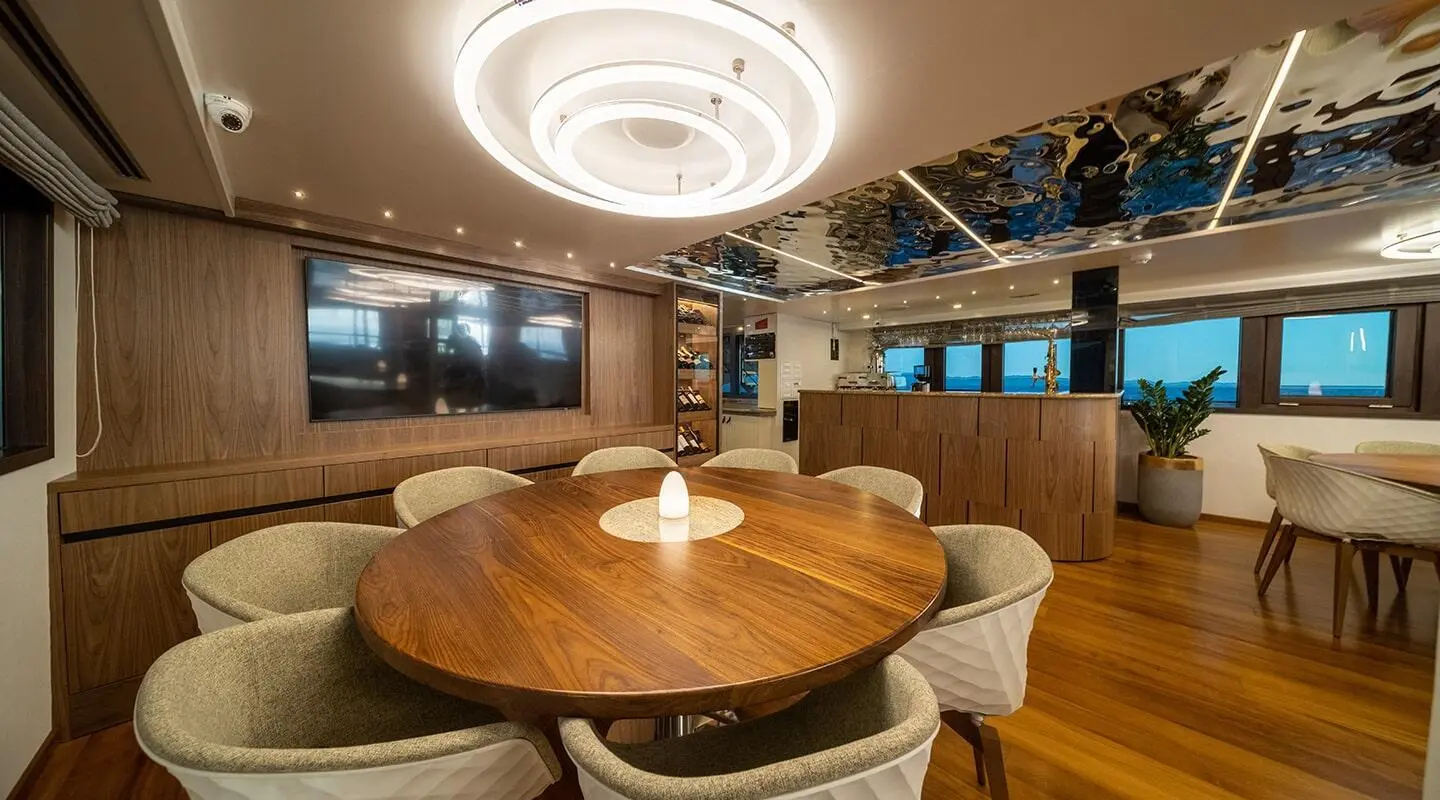 Olimp yacht saloon dining area with round wooden table and plush chairs