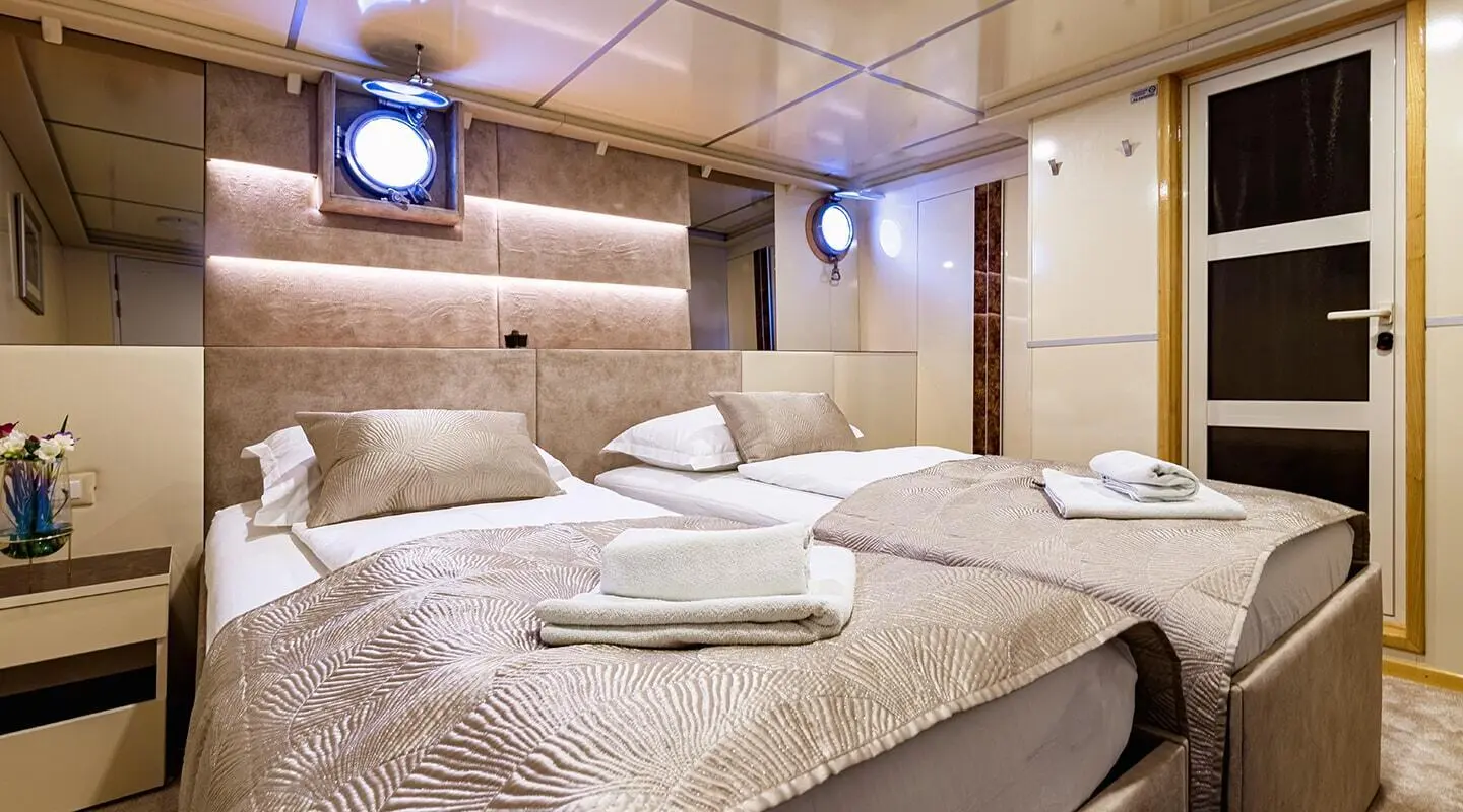 Interior of Melody luxury yacht guest cabin with two beds and warm lighting