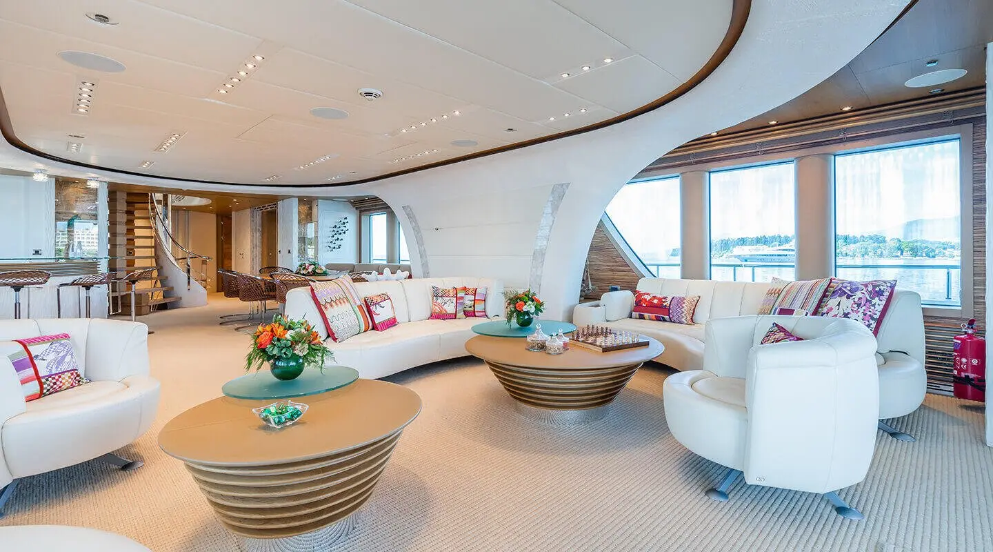 Serenity yacht salon interior at sunset with wicker coffee table and plush seating