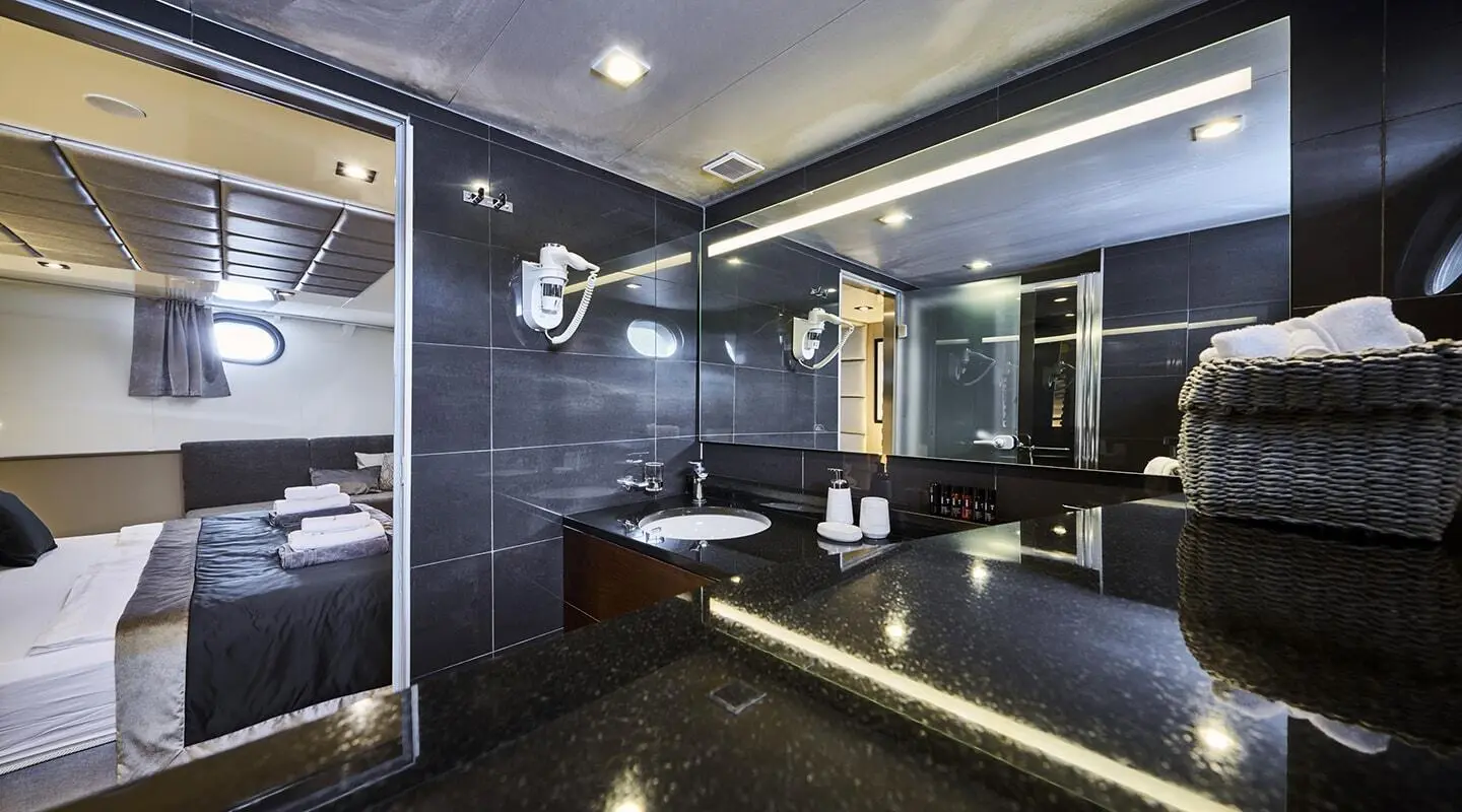 Bathroom aboard yacht Rara Avis with dark blue walls, sink, mirror, and seating