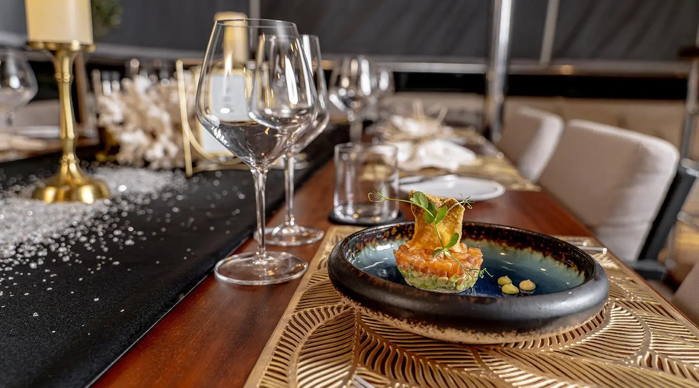 Luxurious yacht Freedom dining setup with plated burger, wine, and candles