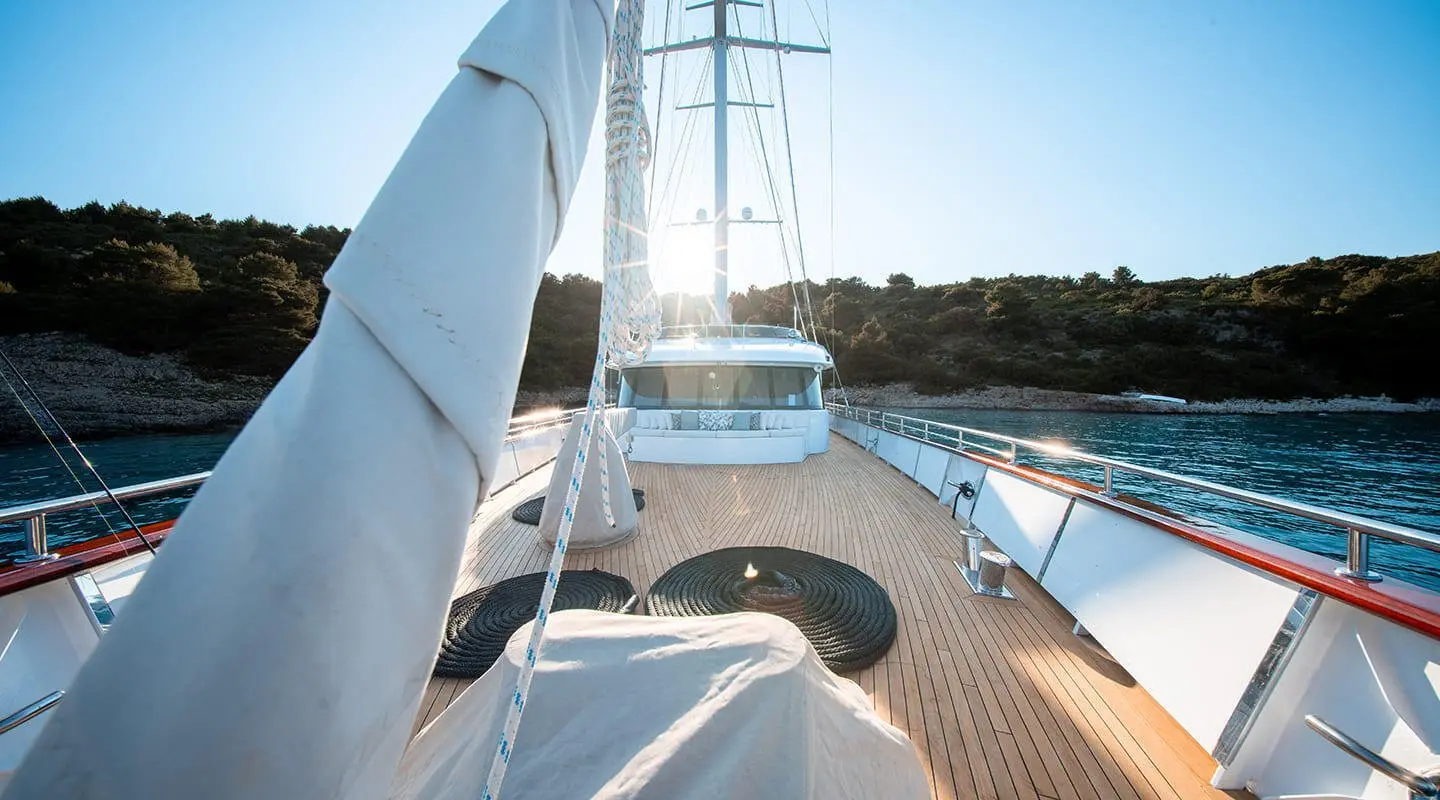 On deck of Nocturno yacht, wooden planks, railing, and blue sky