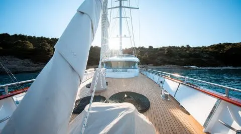 On deck of Nocturno yacht, wooden planks, railing, and blue sky