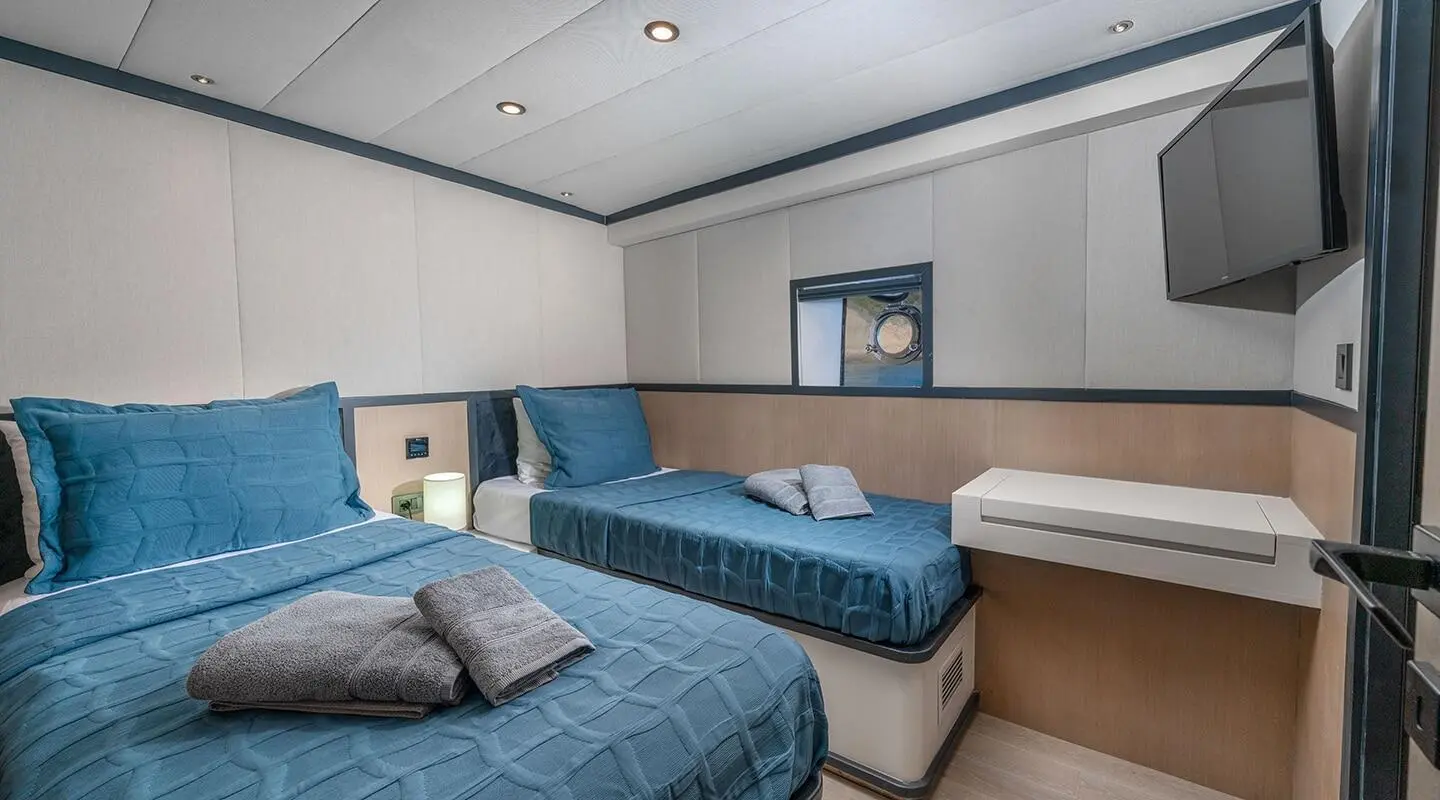 Interior view of Calm Down yacht with two blue beds and a window